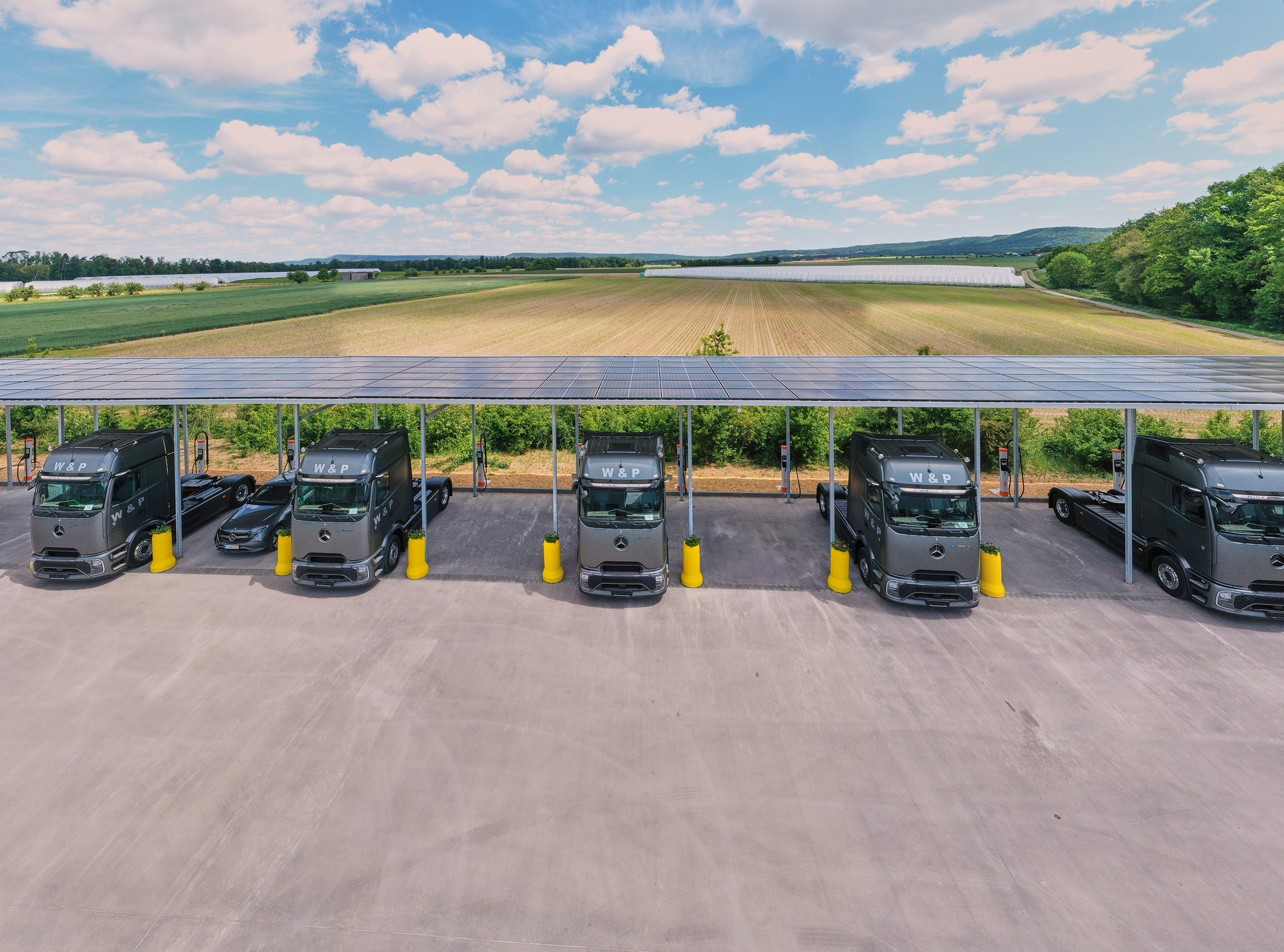 W&P electric trucks parked beneath a solar-powered charging canopy in Bavaria